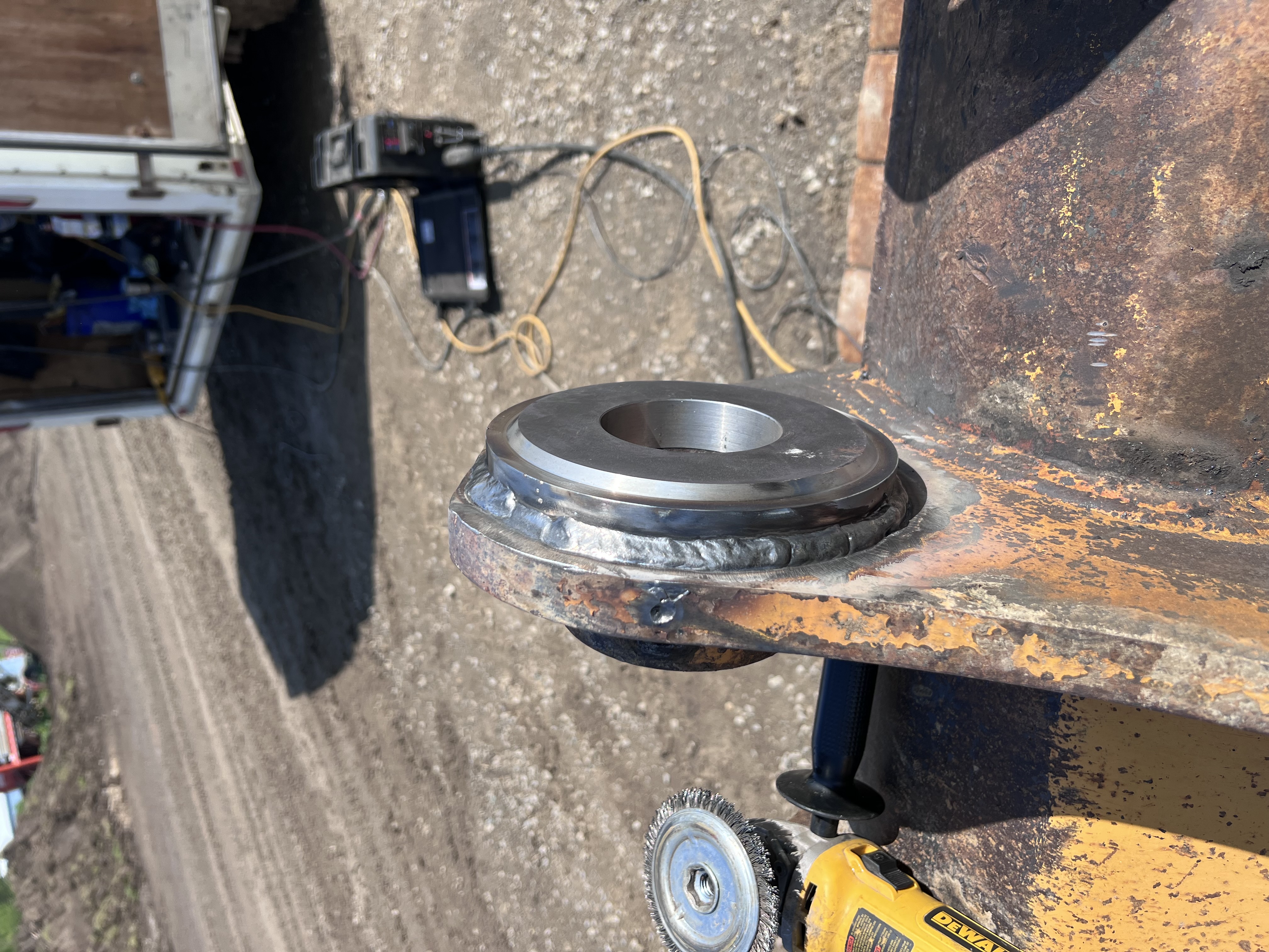 Close-up on a heavy machinery wheel hub/axle component, showing wear/potential repair area.
