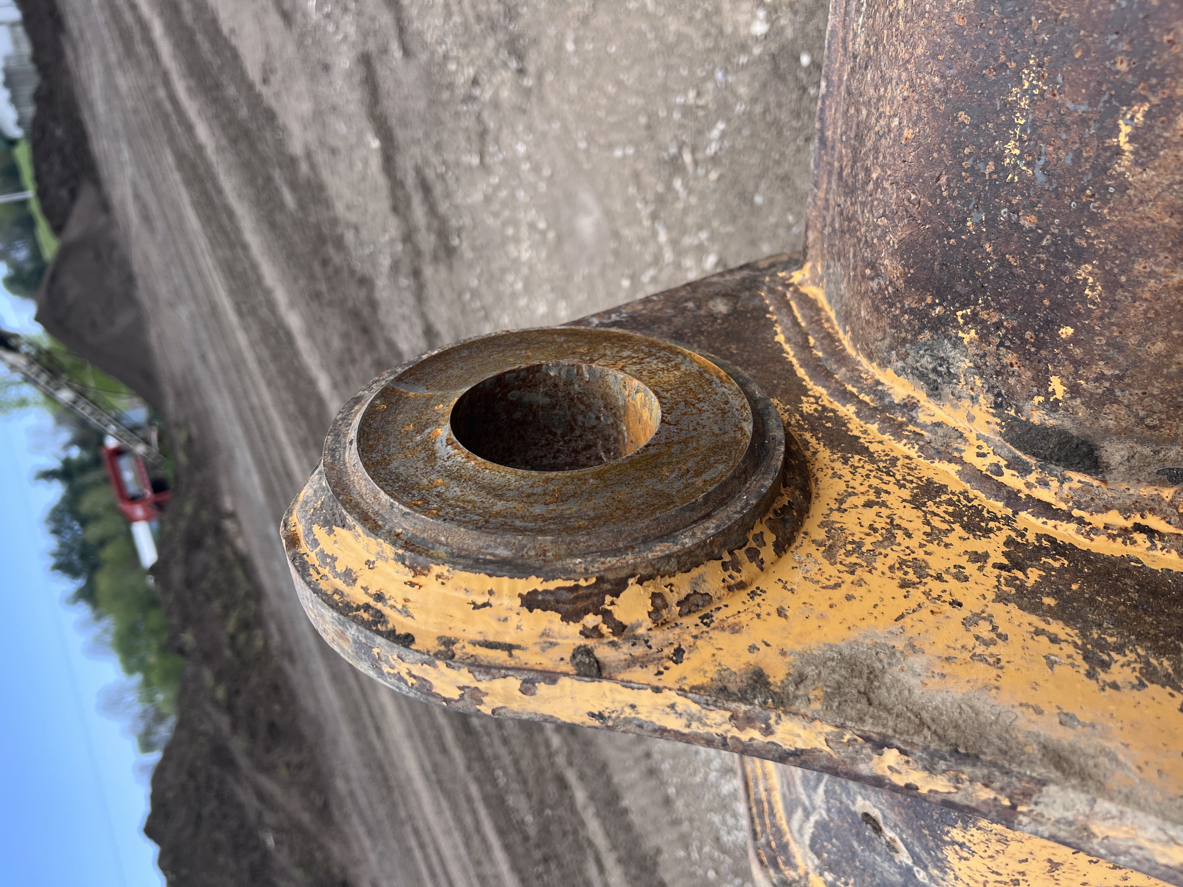 Close-up of a pin and boss joint from heavy equipment, showing grease and wear. Represents equipment repair needs.