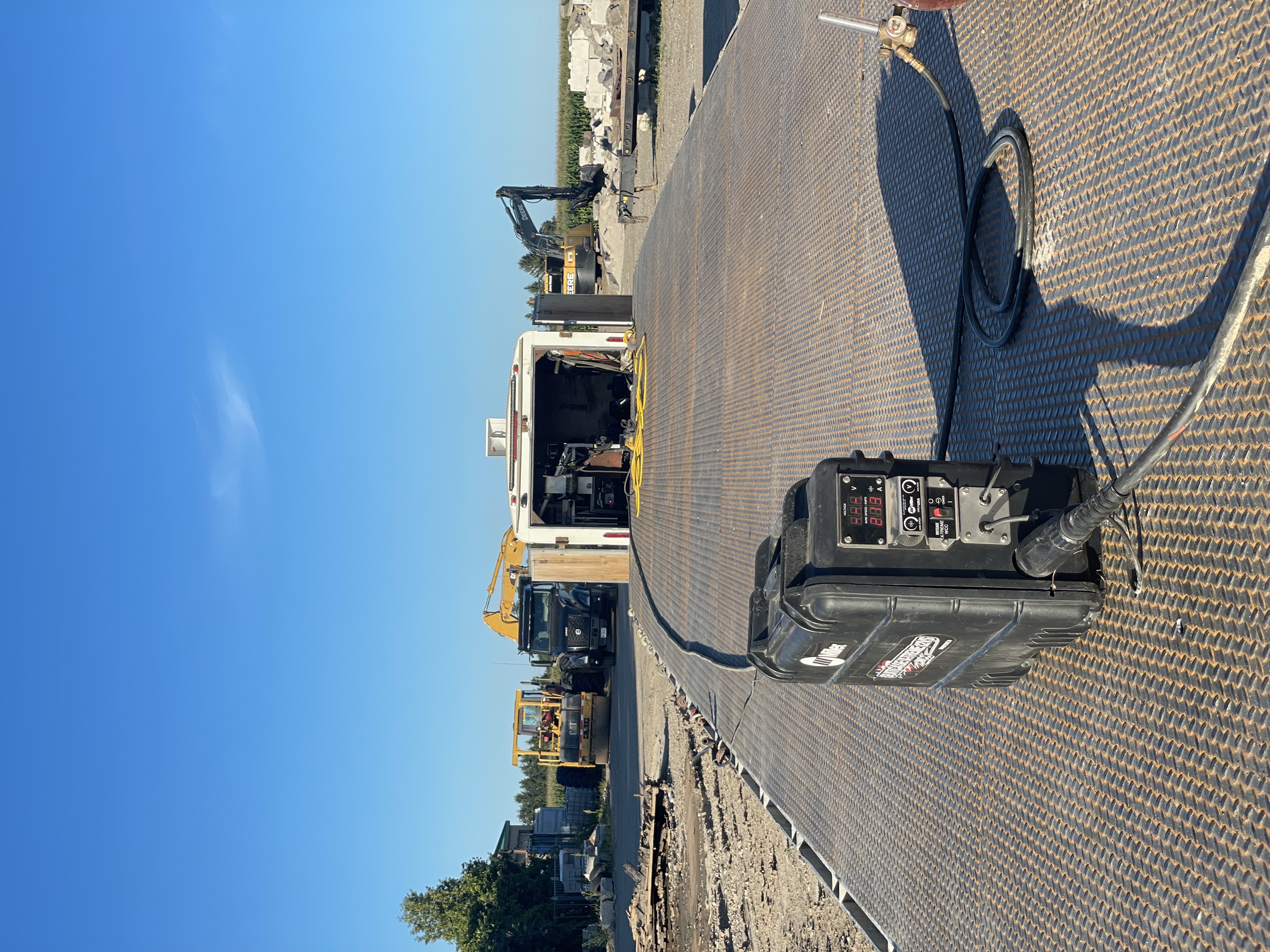 Mobile welding equipment (welder, leads) laid out on pavement outdoors. Shows on-site setup.